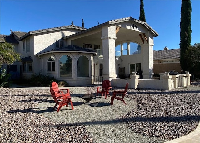 back of property featuring stucco siding, an outdoor fire pit, and a patio