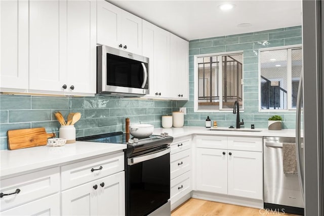 kitchen with light countertops, backsplash, appliances with stainless steel finishes, and a sink