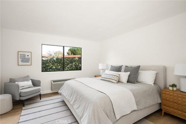 bedroom with a wall mounted air conditioner and light wood-style floors