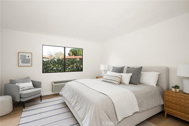 bedroom with a wall unit AC and light wood-type flooring
