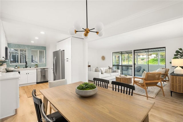 dining room with an inviting chandelier, recessed lighting, light wood finished floors, and crown molding