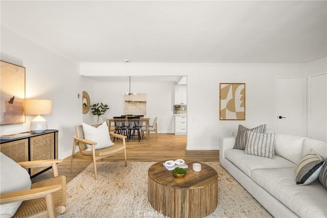 living area featuring baseboards, wood finished floors, and ornamental molding