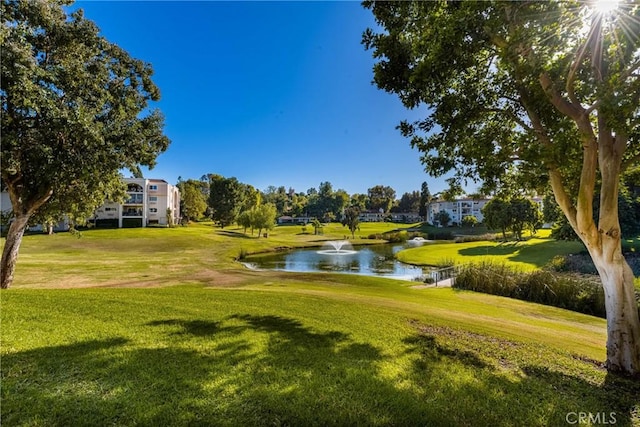 surrounding community with a lawn, view of golf course, and a water view