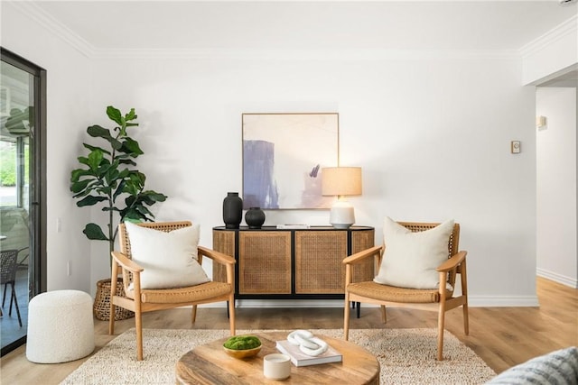 sitting room featuring baseboards, wood finished floors, and ornamental molding