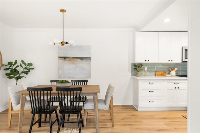 dining room featuring crown molding, light wood-style flooring, baseboards, and a chandelier