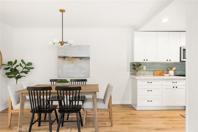 dining area featuring light wood-style floors, baseboards, ornamental molding, and an inviting chandelier
