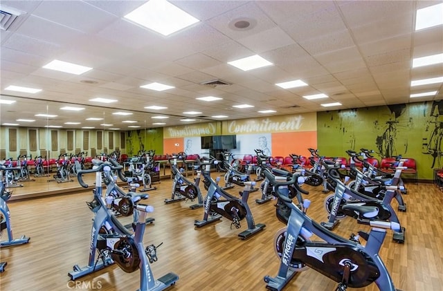 exercise room featuring wood finished floors, visible vents, and a drop ceiling