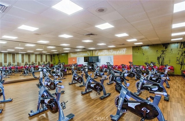 exercise room featuring a paneled ceiling, visible vents, and wood finished floors