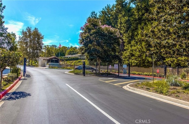 view of street with a gated entry, a gate, and curbs
