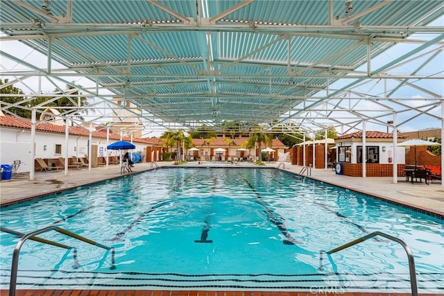 pool featuring a patio, fence, and an outbuilding