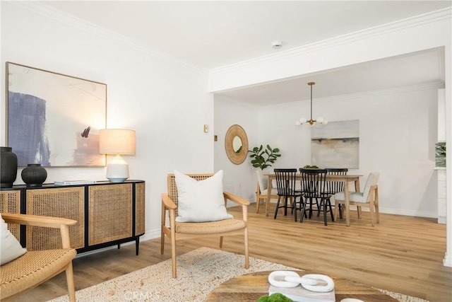 living area with baseboards, a notable chandelier, wood finished floors, and ornamental molding