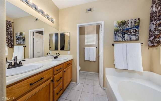 bathroom with vanity, toilet, tile patterned flooring, and a tub