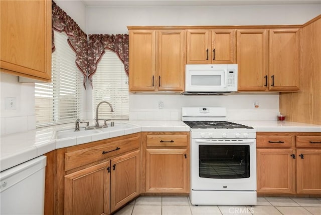 kitchen with light tile patterned floors, sink, tile countertops, and white appliances