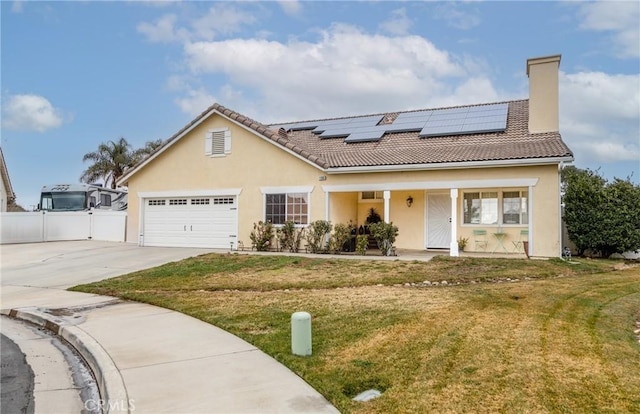 view of front of house with a front lawn, a garage, a porch, and solar panels