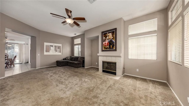 unfurnished room featuring ceiling fan, light carpet, and a tiled fireplace