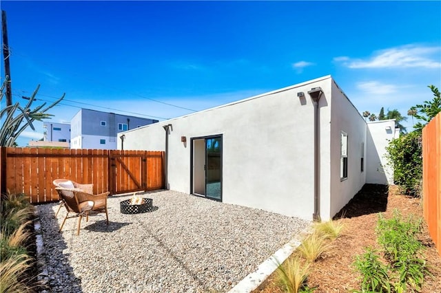 back of property with an outdoor fire pit, a fenced backyard, and stucco siding