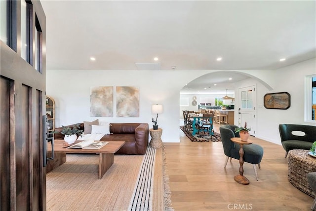 living room with light wood-type flooring, arched walkways, and recessed lighting