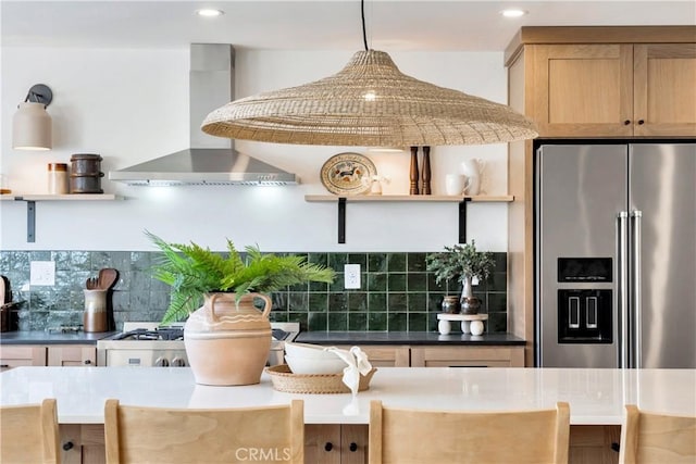 kitchen with decorative light fixtures, wall chimney range hood, backsplash, and high end fridge