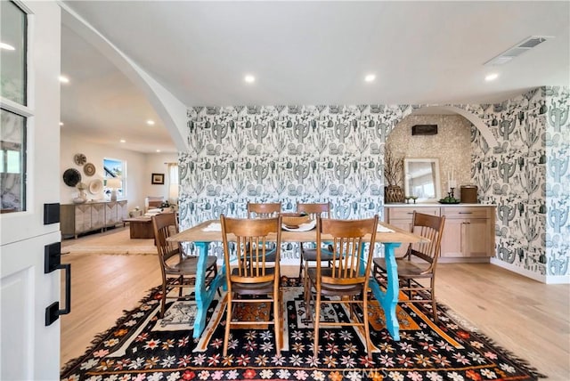 dining area featuring arched walkways, visible vents, and wallpapered walls