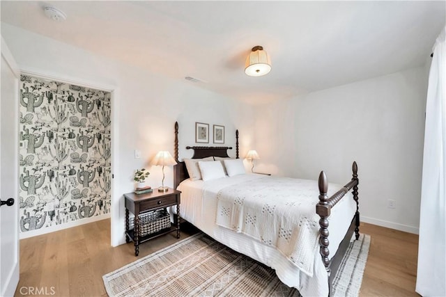 bedroom with visible vents, baseboards, and wood finished floors