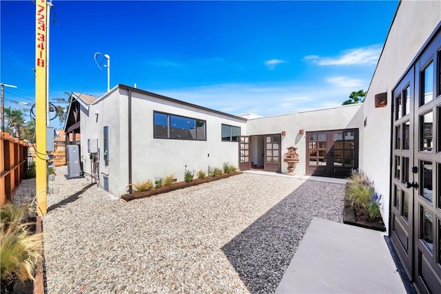 view of front of house featuring a patio, fence, french doors, and stucco siding