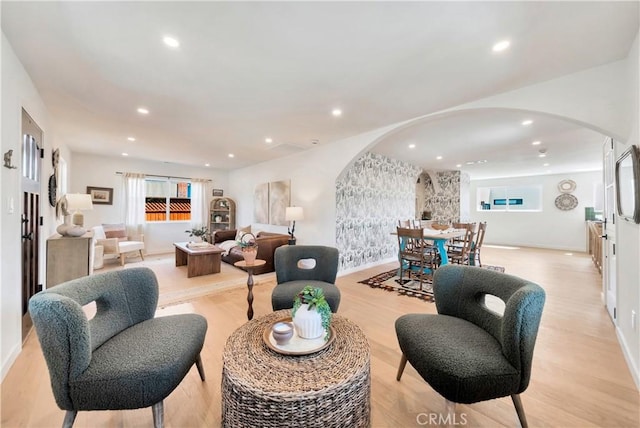 living room featuring arched walkways, light wood-style flooring, baseboards, and recessed lighting