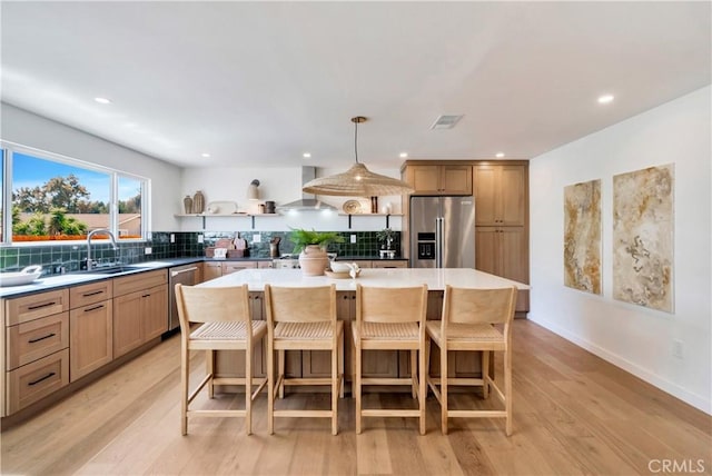 kitchen featuring appliances with stainless steel finishes, wall chimney range hood, backsplash, a center island, and open shelves