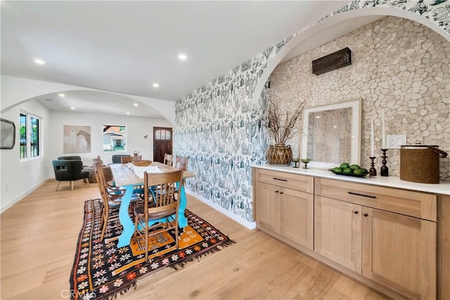 dining space featuring wallpapered walls, baseboards, arched walkways, light wood-style floors, and recessed lighting