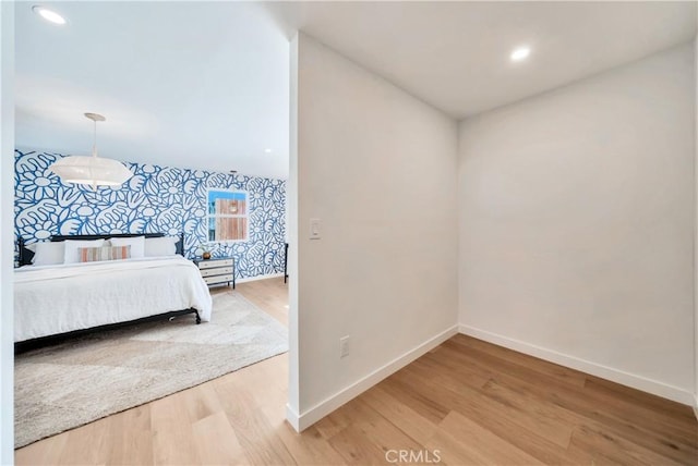 bedroom featuring an accent wall, baseboards, and wood finished floors