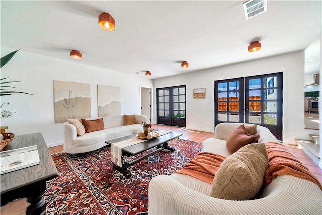 living room featuring tile patterned flooring, french doors, visible vents, and baseboards