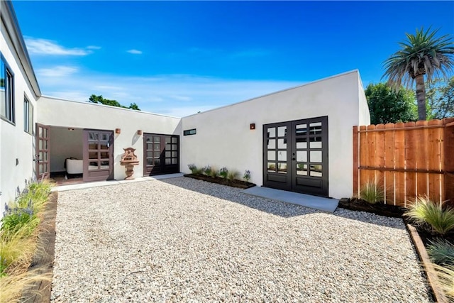 view of front of property with french doors, fence, a patio, and stucco siding