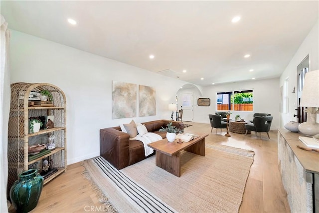 living area featuring light wood finished floors, baseboards, arched walkways, and recessed lighting