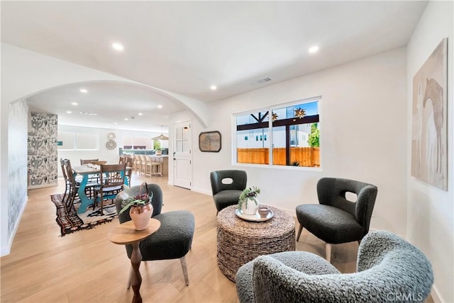 sitting room featuring light wood-style floors, arched walkways, visible vents, and recessed lighting