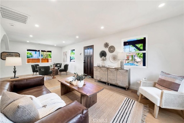 living room with light wood-style flooring, visible vents, baseboards, and recessed lighting