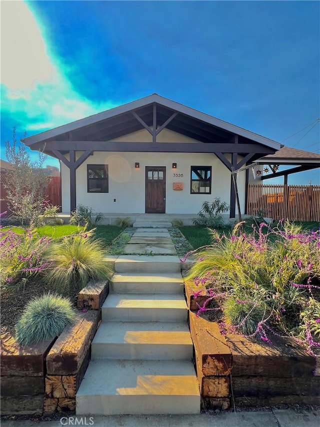 view of front facade with fence, a porch, and stucco siding