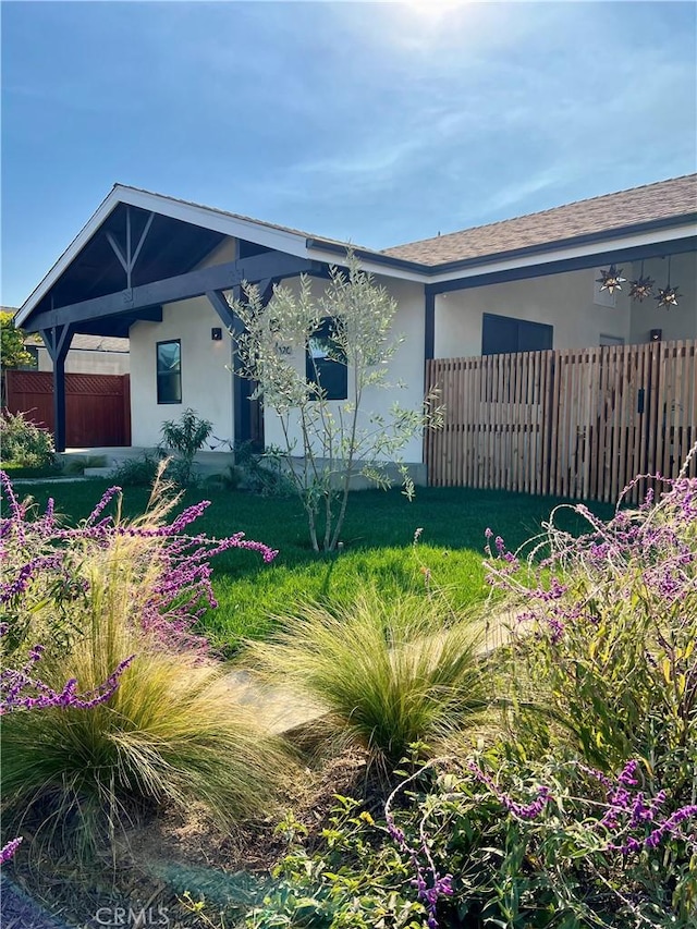 view of front of property with roof with shingles, fence, and stucco siding