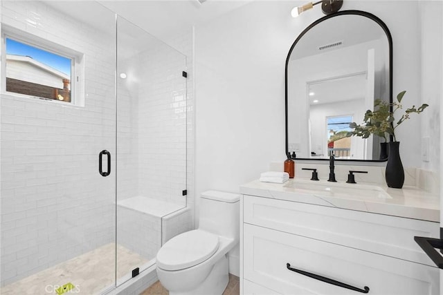 bathroom featuring toilet, a healthy amount of sunlight, vanity, and a shower with door