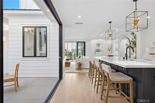 interior space featuring an inviting chandelier, light hardwood / wood-style floors, wood walls, decorative light fixtures, and white cabinets