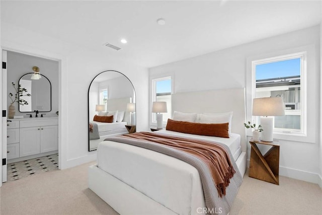 carpeted bedroom with sink and ensuite bathroom