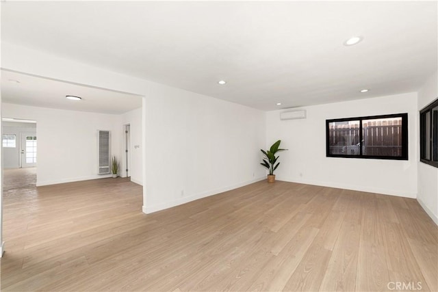 empty room with a wall mounted air conditioner and light hardwood / wood-style flooring