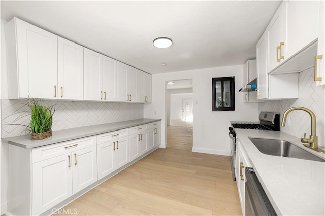 kitchen featuring appliances with stainless steel finishes, extractor fan, white cabinetry, light hardwood / wood-style floors, and sink