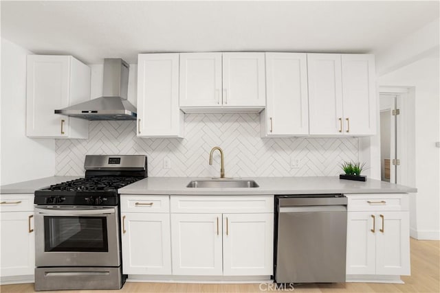 kitchen featuring sink, white cabinetry, appliances with stainless steel finishes, and wall chimney exhaust hood