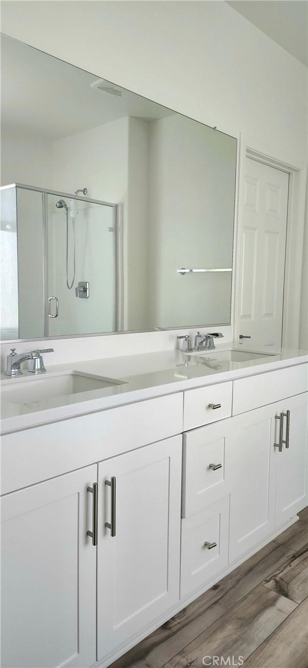 bathroom featuring a shower with door, hardwood / wood-style floors, and vanity