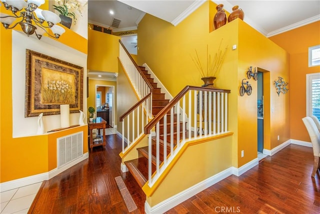 stairway featuring a chandelier, crown molding, and wood-type flooring