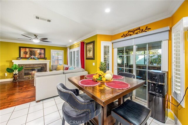 tiled dining area featuring ceiling fan and crown molding