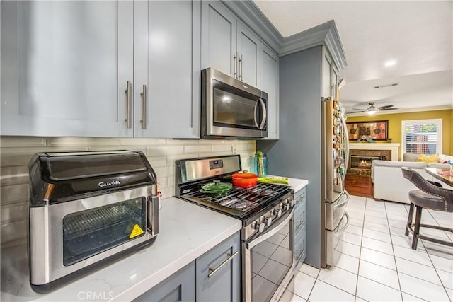 kitchen with light tile patterned flooring, gray cabinets, stainless steel appliances, and tasteful backsplash