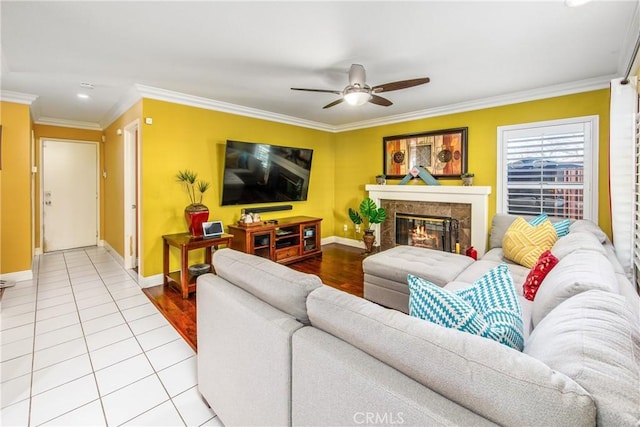 tiled living room featuring a premium fireplace, ornamental molding, and ceiling fan