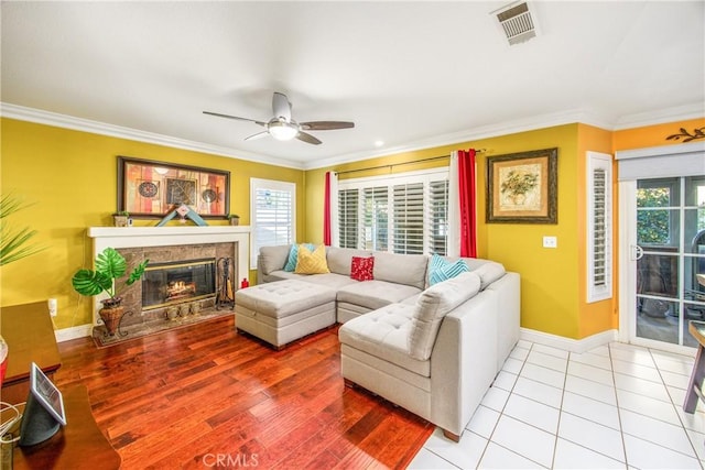 tiled living room with ceiling fan, plenty of natural light, and ornamental molding