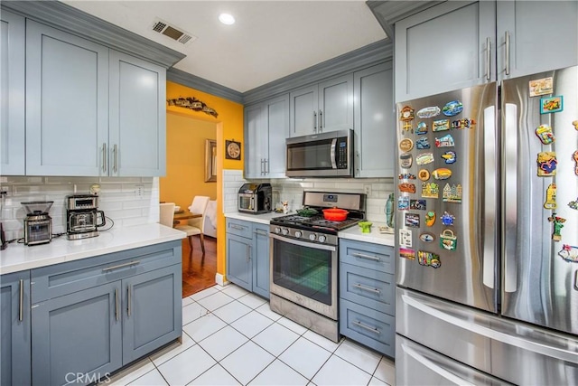 kitchen featuring light tile patterned floors, appliances with stainless steel finishes, crown molding, and backsplash