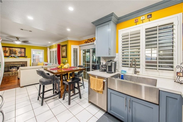 kitchen with ceiling fan, light tile patterned floors, stainless steel dishwasher, and ornamental molding